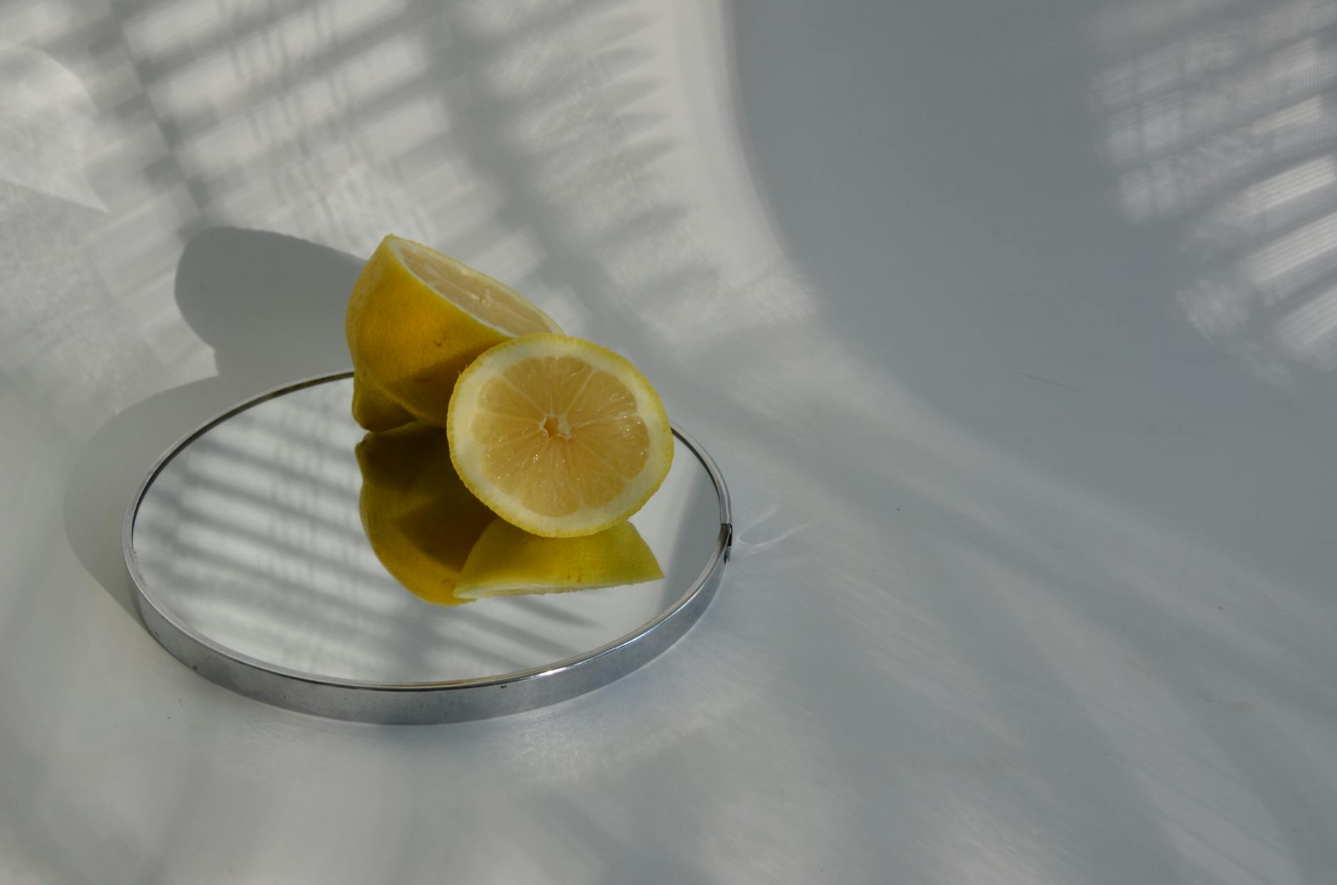 Sliced lemons on a mirror with soft shadows, representing the refined simplicity of pleasure after 40