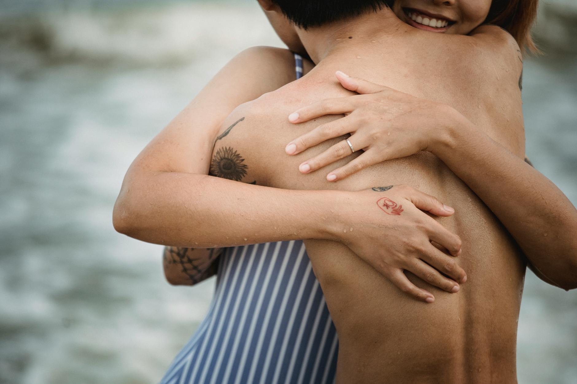 A couple shares a tender kiss under a cozy white blanket, showing emotional closeness and affection