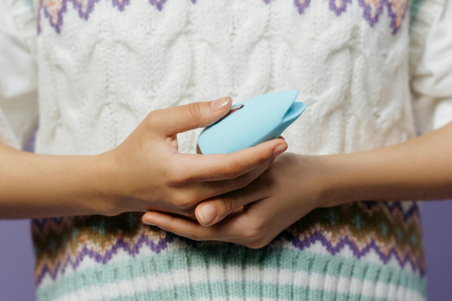 A blue silicone sex toy held in hand against a solid purple background, promoting self-love and sexuality.